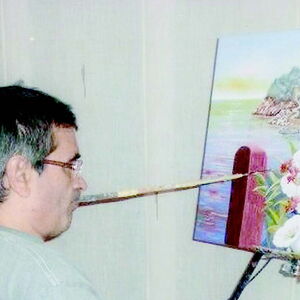 Mundmaler Francisco Palos Jiménez beim Malen eines Bildes mit seinem Mund